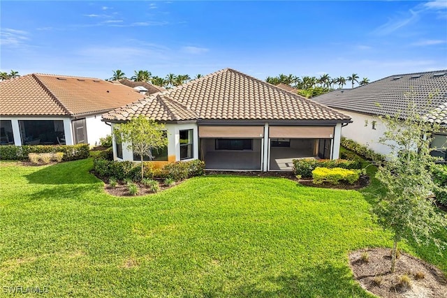 rear view of property featuring a lawn and a sunroom