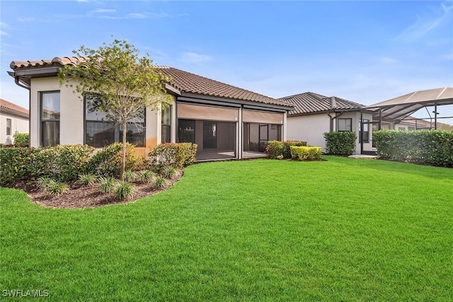 back of house with a lanai and a lawn