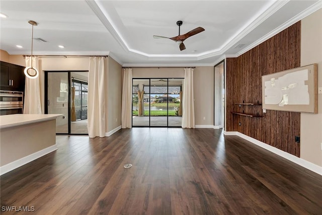 unfurnished living room with dark hardwood / wood-style flooring, a tray ceiling, ornamental molding, and ceiling fan