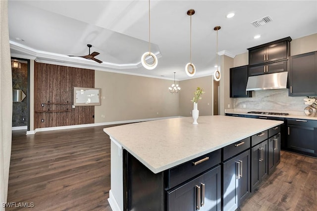 kitchen featuring crown molding, decorative light fixtures, dark hardwood / wood-style floors, a kitchen island, and decorative backsplash