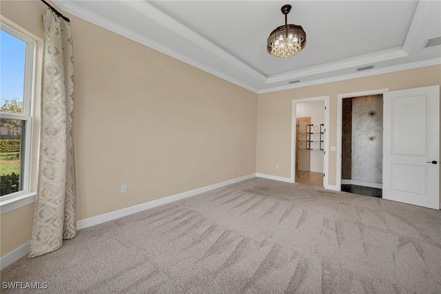 unfurnished bedroom featuring crown molding, ensuite bath, a tray ceiling, carpet floors, and a chandelier