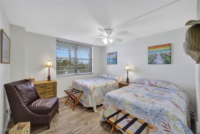 bedroom with ceiling fan, a textured ceiling, and light hardwood / wood-style flooring