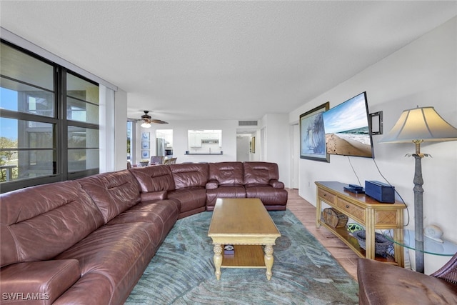 living room with ceiling fan, wood-type flooring, and a textured ceiling