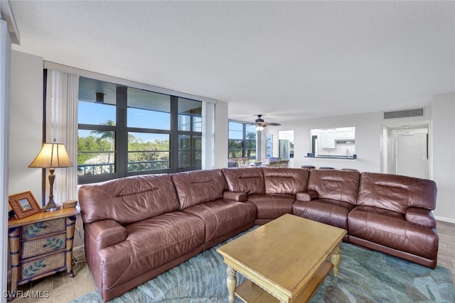 living room with hardwood / wood-style floors, ceiling fan, and a textured ceiling