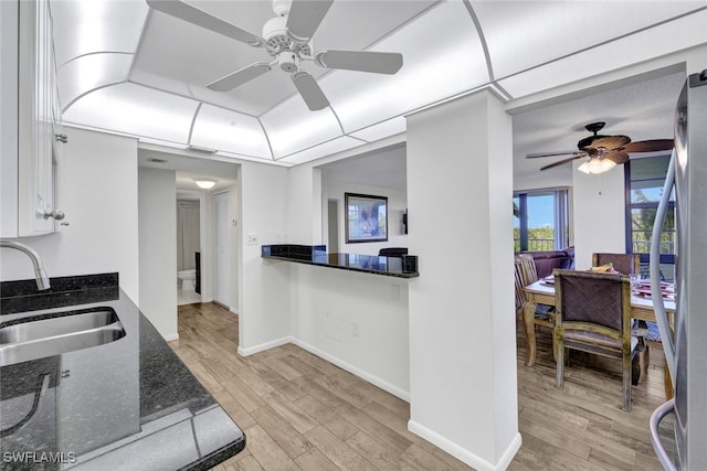 kitchen with stainless steel fridge, light wood-type flooring, ceiling fan, sink, and white cabinets