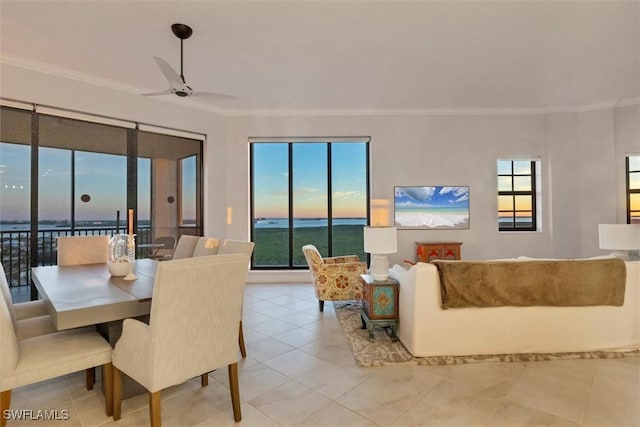 tiled dining area with ceiling fan, crown molding, and a water view