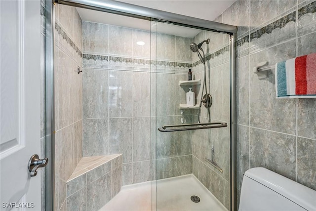 bathroom featuring toilet and a shower with door