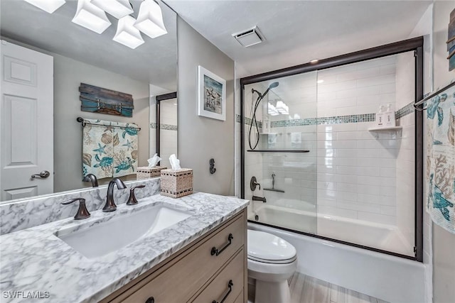 full bathroom featuring combined bath / shower with glass door, vanity, and toilet