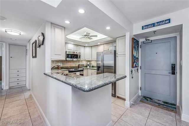 kitchen featuring kitchen peninsula, sink, ceiling fan, appliances with stainless steel finishes, and white cabinetry