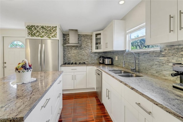 kitchen with wall chimney exhaust hood, sink, white cabinetry, appliances with stainless steel finishes, and light stone countertops