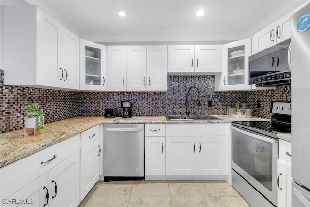 kitchen with white cabinetry, stainless steel appliances, sink, and light stone counters