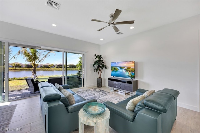 living room featuring ceiling fan and a water view