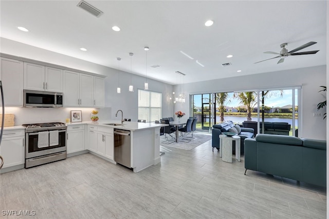 kitchen with sink, kitchen peninsula, decorative light fixtures, a water view, and appliances with stainless steel finishes