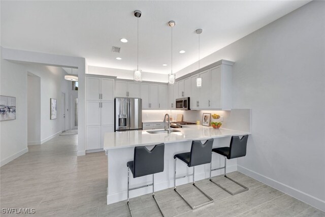 12418 Dahlia Ct, Naples, FL 34120 - kitchen featuring stainless steel appliances, a sink, a peninsula, light countertops, and a kitchen breakfast bar
