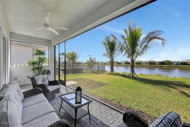 sunroom / solarium with ceiling fan and a water view