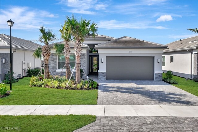 12418 Dahlia Ct, Naples, FL 34120 - prairie-style home featuring a garage, decorative driveway, stone siding, a front lawn, and stucco siding