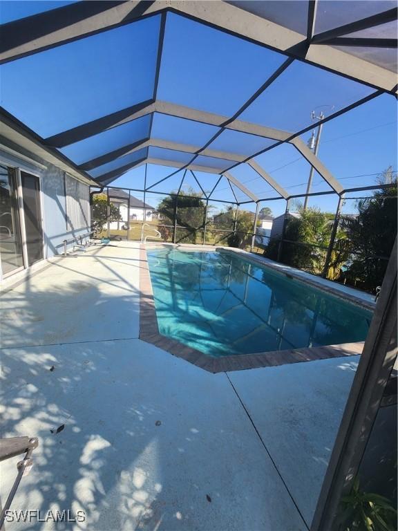 view of pool with glass enclosure and a patio