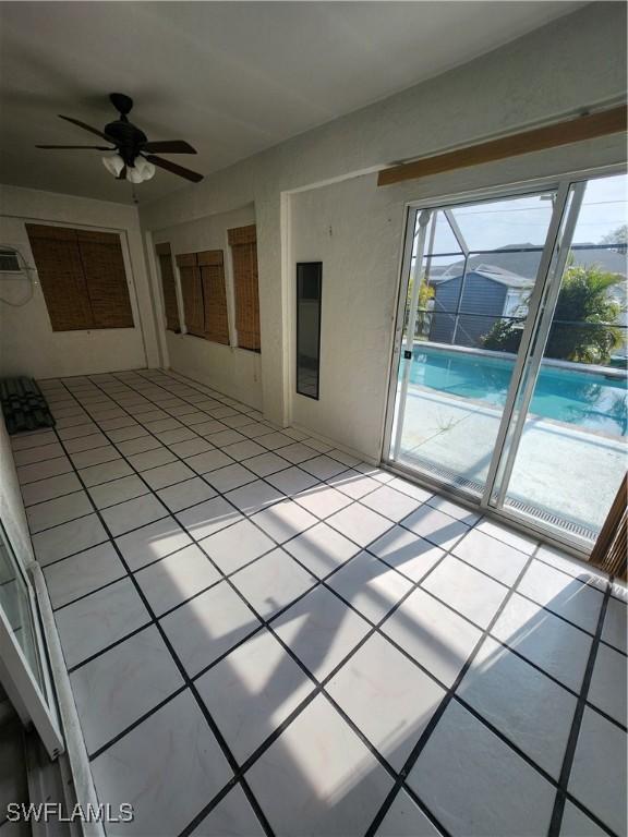 empty room with ceiling fan and light tile patterned floors