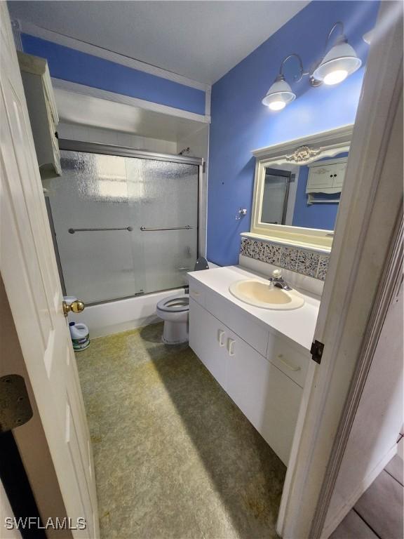 full bathroom featuring toilet, bath / shower combo with glass door, and vanity