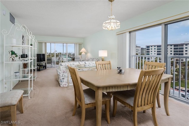 dining space with light carpet and an inviting chandelier