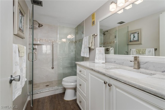 bathroom with hardwood / wood-style floors, vanity, toilet, and a shower with shower door