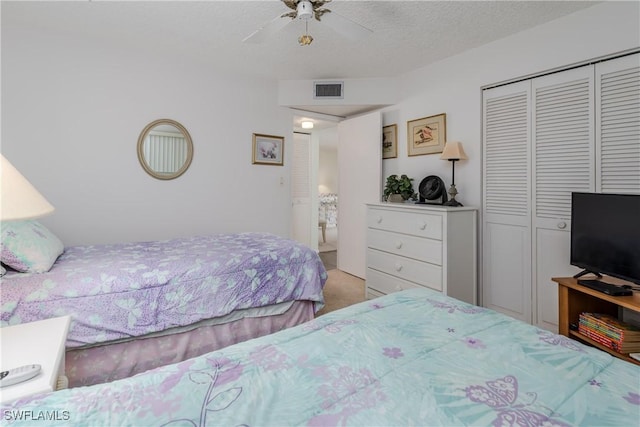 bedroom featuring ceiling fan, a textured ceiling, light carpet, and a closet