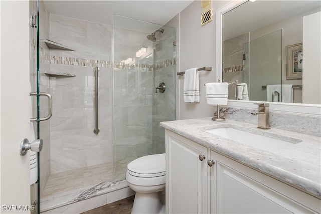 bathroom with vanity, toilet, and a shower with door