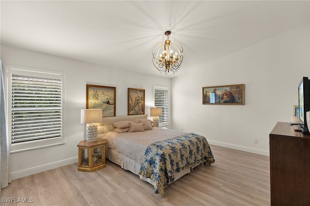 bedroom with light wood-type flooring and a chandelier