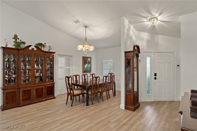 dining area with lofted ceiling, a notable chandelier, and light hardwood / wood-style flooring