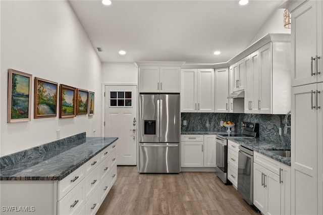 kitchen with white cabinets, stainless steel appliances, light hardwood / wood-style flooring, and decorative backsplash