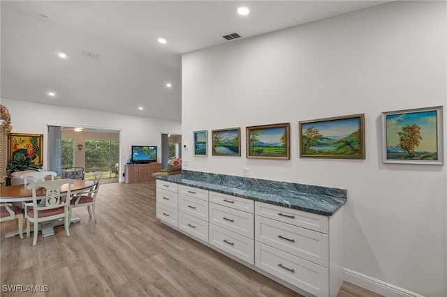 kitchen featuring white cabinets, light hardwood / wood-style flooring, and dark stone counters