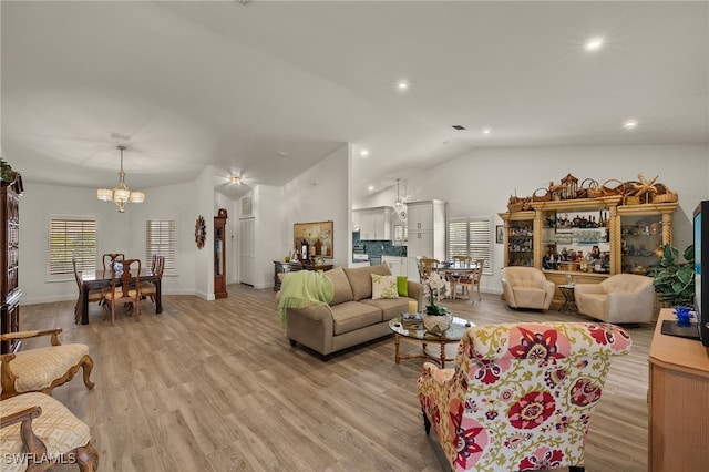 living room with light hardwood / wood-style floors, an inviting chandelier, and lofted ceiling