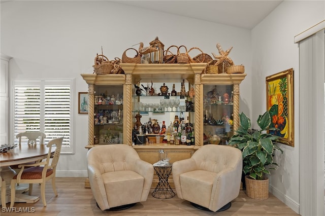 bar with lofted ceiling and light hardwood / wood-style flooring