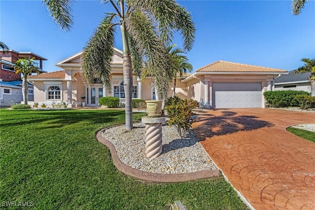 mediterranean / spanish house with a tile roof, stucco siding, a front yard, a garage, and driveway