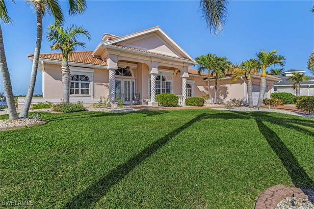 view of front facade featuring a front yard, a garage, and french doors