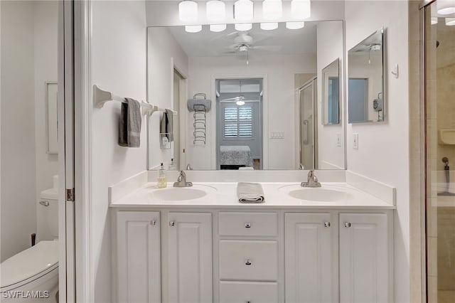 bathroom with vanity, ceiling fan, toilet, and a shower with door