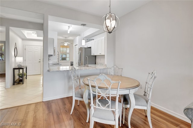 dining room featuring sink, light hardwood / wood-style floors, and ceiling fan with notable chandelier