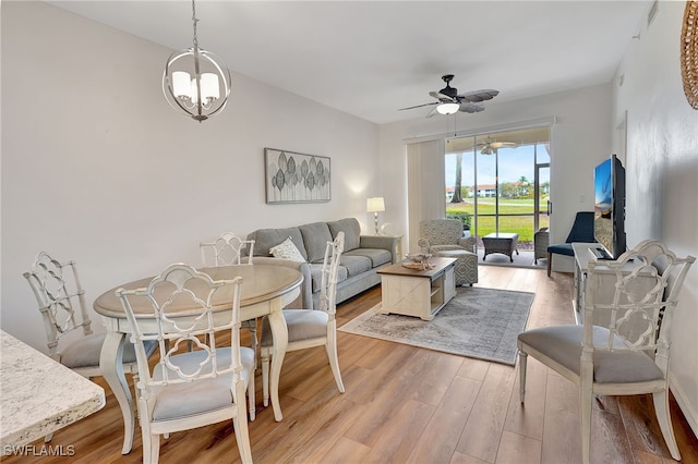 living room featuring ceiling fan with notable chandelier and light hardwood / wood-style flooring