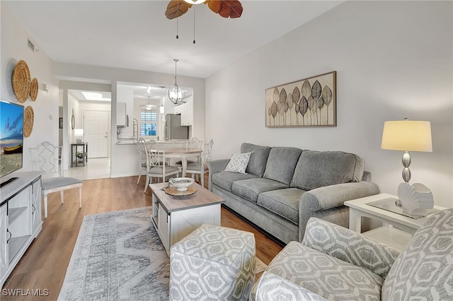 living room featuring hardwood / wood-style floors and ceiling fan with notable chandelier