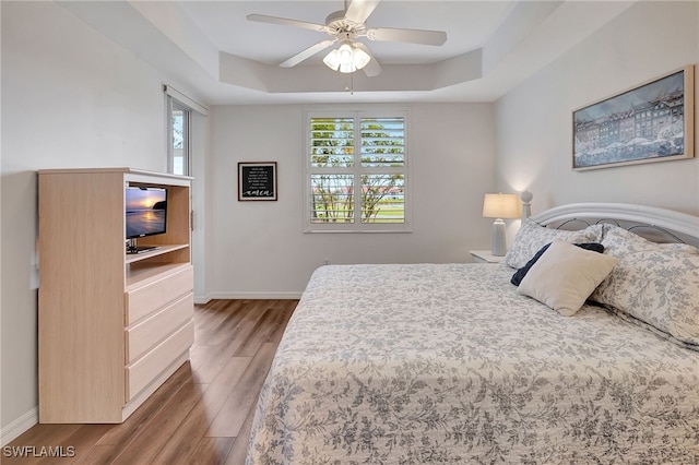 bedroom featuring wood-type flooring, a tray ceiling, and ceiling fan