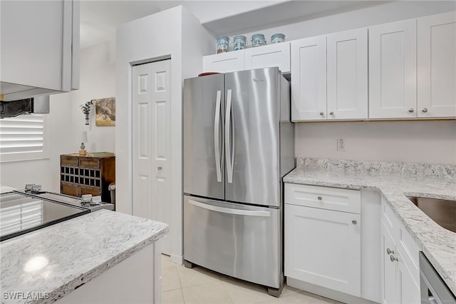 kitchen with light stone counters, white cabinetry, stainless steel appliances, and light tile patterned floors