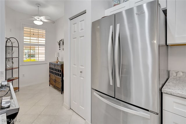 kitchen with stainless steel refrigerator, light stone countertops, white cabinetry, ceiling fan, and light tile patterned flooring