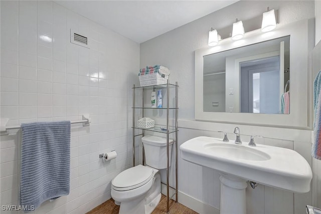 bathroom featuring hardwood / wood-style flooring, tile walls, and toilet