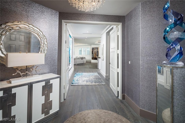 hallway with ornamental molding, dark wood-type flooring, and a notable chandelier