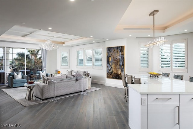 living room featuring a notable chandelier, dark hardwood / wood-style flooring, and a raised ceiling