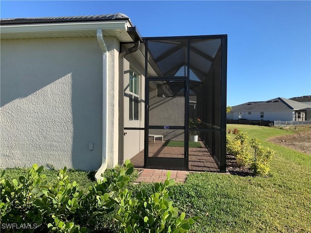 view of side of property with a lanai and a yard