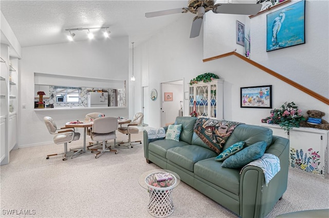 carpeted living room featuring rail lighting, ceiling fan, lofted ceiling, and a textured ceiling