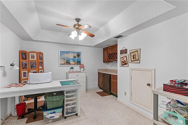 carpeted home office featuring a tray ceiling and ceiling fan