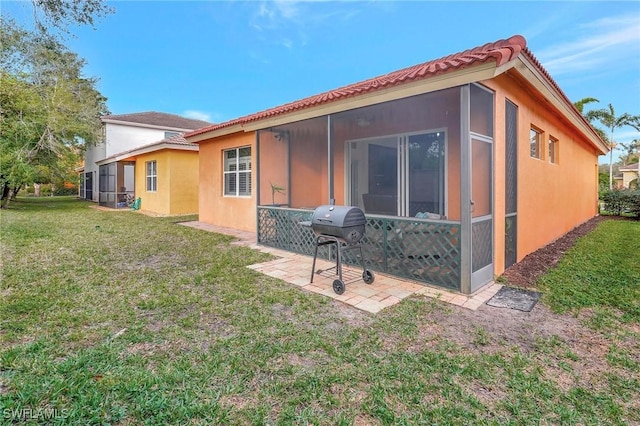 back of property featuring a sunroom, a lawn, and a patio