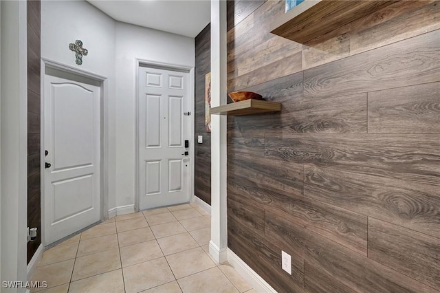 doorway with light tile patterned floors and wood walls